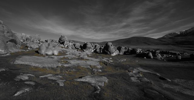 Capture of an expansive rocky wilderness under a dramatic sky tinting the scene in contrasting grays. Ideal for projects emphasizing solitude, timeless beauty, geological studies, nature reserve promotions, or environmental conservation. Perfect cover image for video presentations of untouched landscapes.