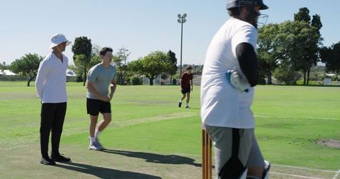 Batsman stepping into crease driving shot during casual cricket match on sunny green field