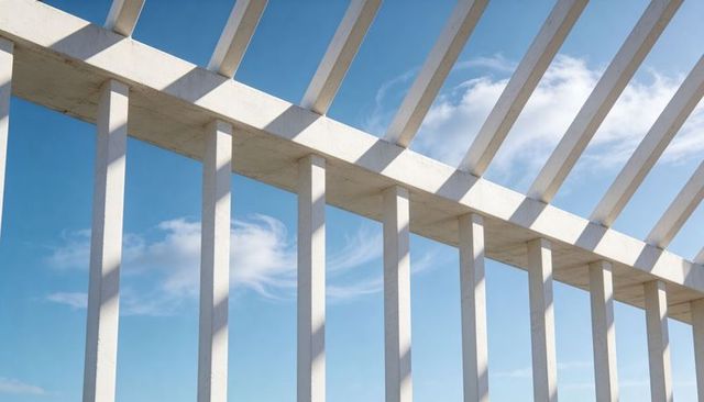 Sunlit white colonnade casting diagonal shadows over blue sky minimalist architectural grid