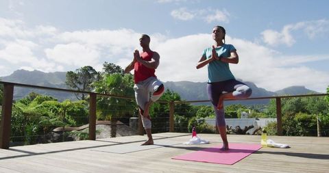 Diverse Couple Doing Tree Pose Yoga Outdoors on Terrace