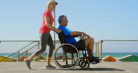 Senior Woman Pushing Man in Wheelchair Outdoors