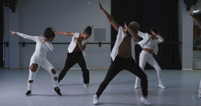 Features group of diverse dancers performing synchronized dance moves in modern dance studio. Suitable for content related to dance, choreography, fitness, teamwork, contemporary arts, dance classes, and creative expressions.