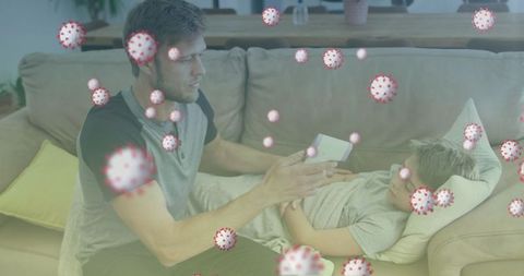 Father monitoring son's fever at home with digital thermometer