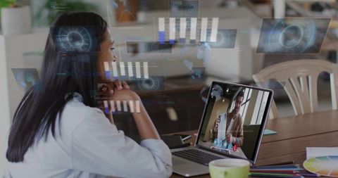 Young woman joining video call with holographic data overlays at wooden home workspace