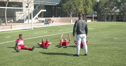 Coach guiding youth soccer players in sit-ups on school field
