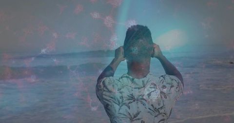 Man filming ocean from shoreline with floral shirt and dreamlike pastel nebula overlay