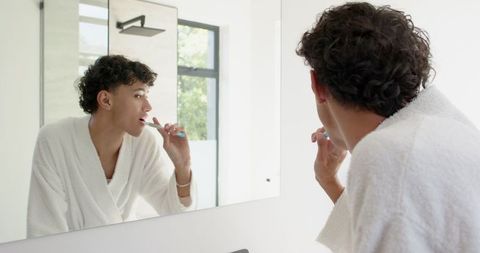 Man brushing teeth performing morning routine in modern bathroom