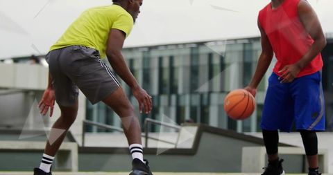 Playing rooftop basketball: dribbling guard facing tight defense on urban court