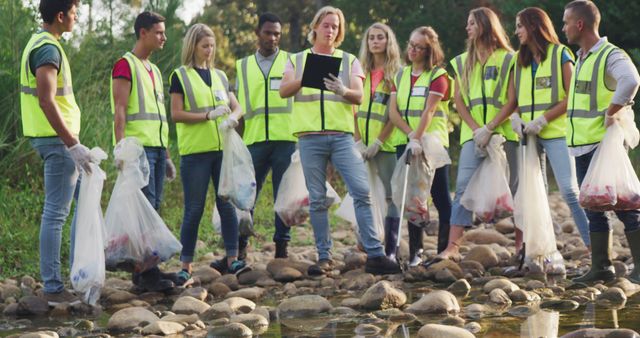 A multi-ethnic group of conservation volunteers wearing hi vis vests, cleaning up a river in the countryside, taking notes. Ecology and social responsibility in a rural environment.