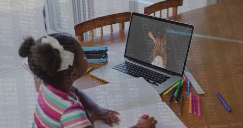Young girl learning online at dining table with laptop, notebook, colorful markers and homework