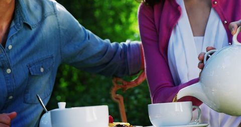 Woman Pouring Tea at Relaxing Outdoor Picnic