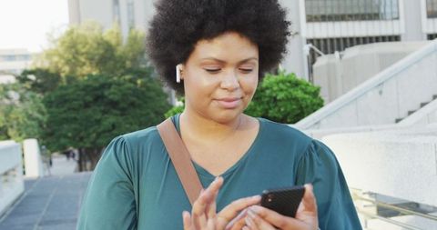 Confident Plus Size Biracial Woman with Smartphone and Earphones Outdoors
