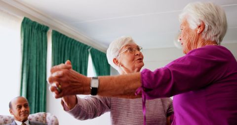 Senior Women Joyfully Dancing Together in Nursing Home