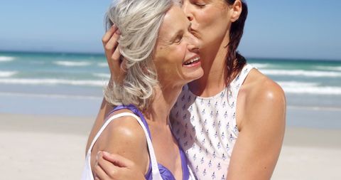 Mother and Daughter Embracing on Sunny Beach Reflecting Joyful Bond