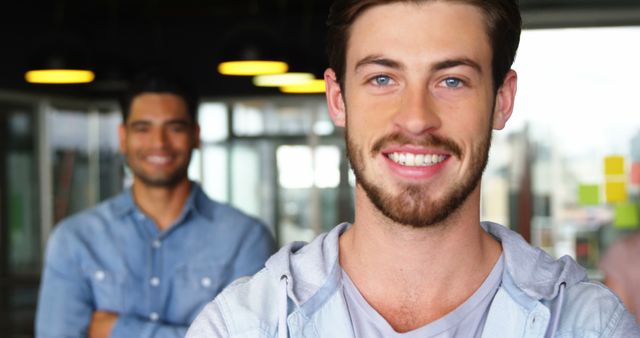 Smiling Young Man in Casual Clothing with Colleague in Background - Download Free Stock Images Pikwizard.com