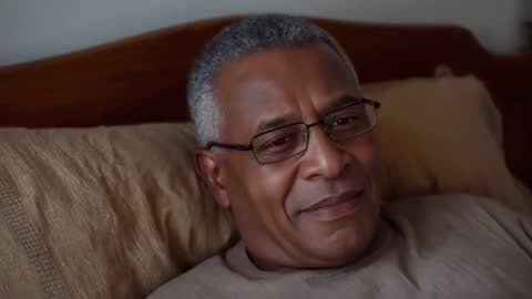 Reclining mature man wearing glasses and smiling during bedside conversation, serene home