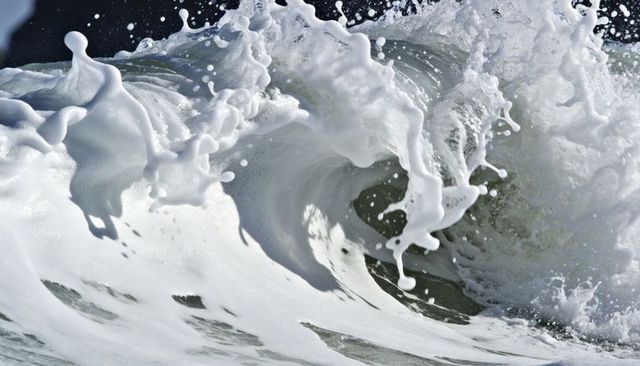 Crashing ocean wave curling barrel with thick white foam and dramatic sea spray close-up