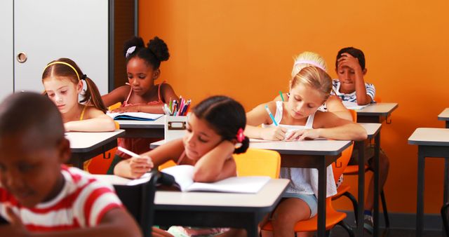 Image shows a diverse group of elementary students studying and writing in a classroom. Can be used for educational materials, school promotions, learning resources, teaching guides, and articles about diversity in education.