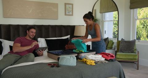 Couple packing suitcase in bedroom for event travel