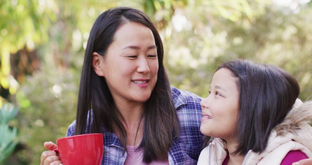 Image of happy asian mother and daughter embracing and talking in garden. Family, motherhood, relations and spending quality time together concept digitally generated image.