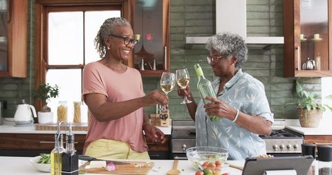 Senior Women Toasting with Wine in Modern Kitchen