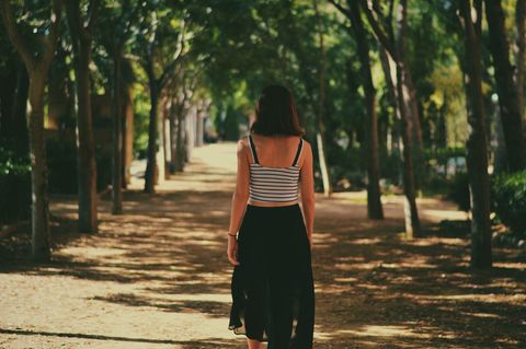Woman Walking Down Tranquil Tree-Lined Pathway