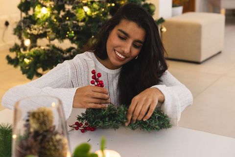 South asian woman crafting pine wreath for christmas decorations