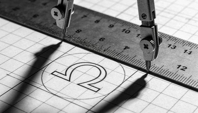 Precision compass drawing omega symbol on engineering grid ruler and measuring instruments