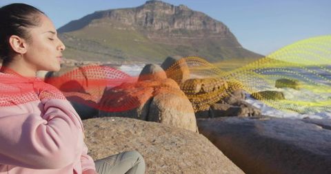 Mindful woman meditating by ocean with digital waves