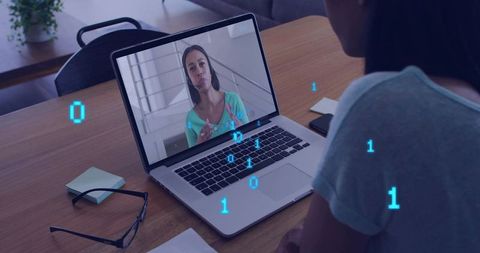 Woman video chatting on laptop in home workspace with binary code overlay for remote work