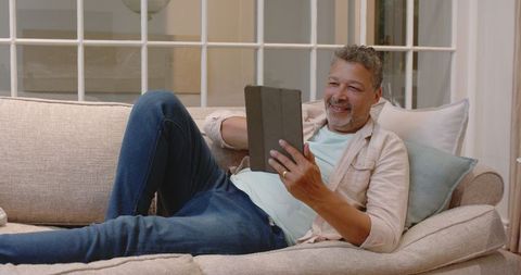 Senior Man Relaxing with Tablet on Comfortable Sofa