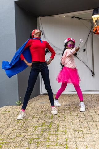 Preteen african american girls posing in superhero and fairy costumes for halloween
