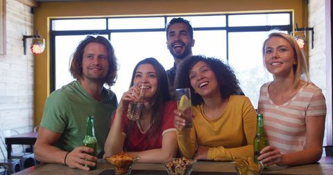 Friends Enjoying Drinks at Bar During Sports Game