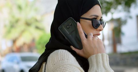 Modern Woman in Hijab Talking Smartphone Outdoors