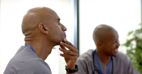 African american male nurse pondering during team meeting in clinic healthcare teamwork
