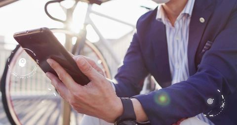 Mature asian businessman using tablet on boardwalk with bicycle at golden hour