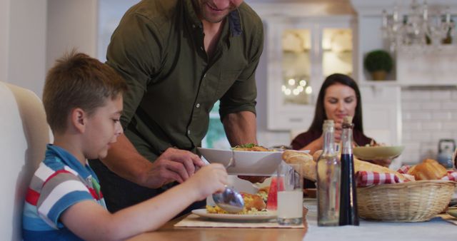 Smiling caucasian father standing at table serving son food before family meal - Download Free Stock Photos Pikwizard.com