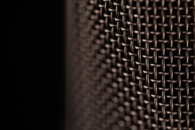 The image shows a detailed close-up of a metallic mesh grid. The texture and pattern of the grid are prominent, with a soft focus effect creating an abstract feel. This can be used in a variety of design projects, including backgrounds for technology-related graphics, industrial-themed projects, or as a texture study in artistic works.