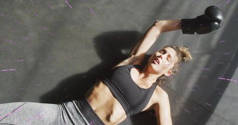 Exhausted athlete lying after boxing workout, catching breath on gym mat