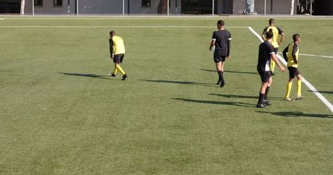 Soccer Players Strategizing During Friendly Match on Green Field