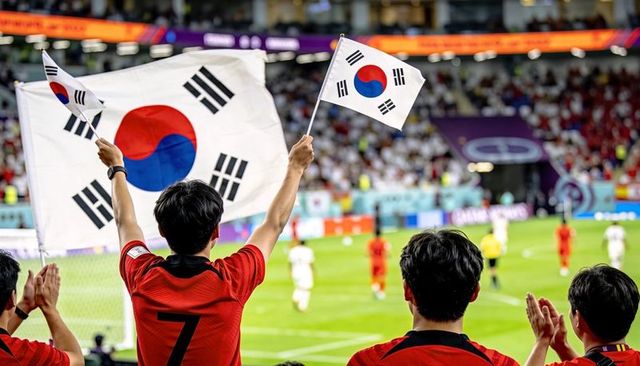 South korean fans waving taegeukgi flags in stadium during intense night soccer match