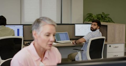 Open plan office with diverse team using dual monitors for collaboration