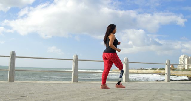 Woman with prosthetic leg jogging by the ocean on sunny day - Download Free Stock Images Pikwizard.com