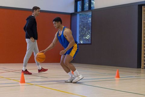 Basketball dribbling practice in indoor gym with coach