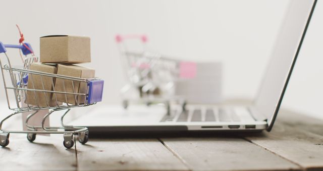 Boxes in shopping trolley beside laptop on desk. Global business, online shopping, cyber monday, sale and retail concept digitally generated image.