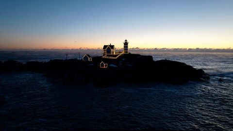 Lighthouse at dawn with holiday lights silhouette