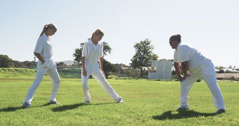 Female Athletes in Uniform Performing Warm-up Exercises on Sports Field