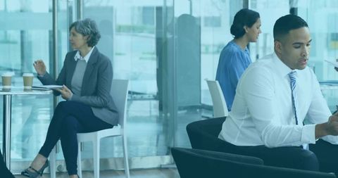 Businessman Checking Phone while Professionals Wait in Modern Glass Office Lobby