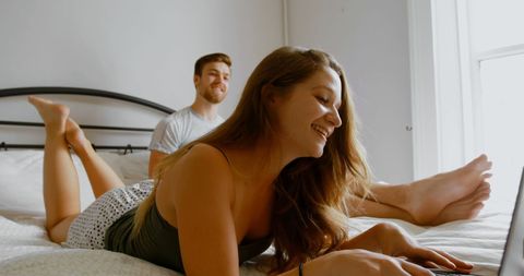Couple relaxing with laptop on bed in cozy home interior