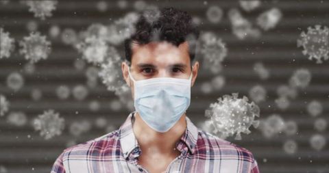 Young adult male wearing mask amid floating virus particles